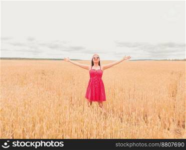Beautiful woman in red retro dress standing in golden field. Freedom concept. Happy lady outdoors. Harvest, agriculture concept. High quality photo. Beautiful woman in red retro dress standing in golden field. Freedom concept. Happy lady outdoors. Harvest, agriculture concept.