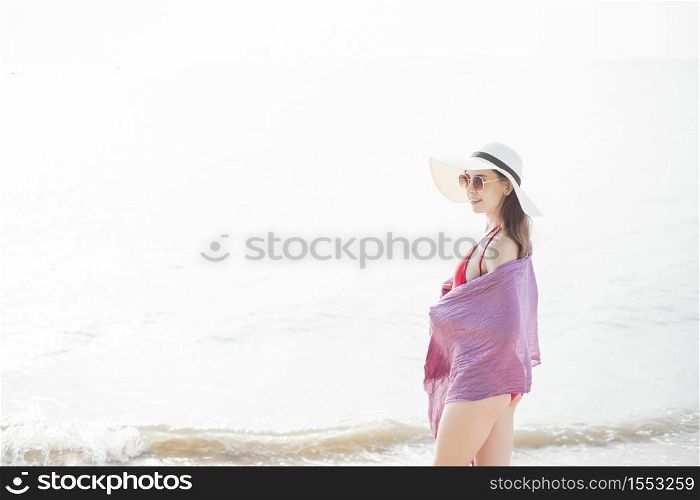 Beautiful woman in red swimsuit is relaxing on the beach, summer concept