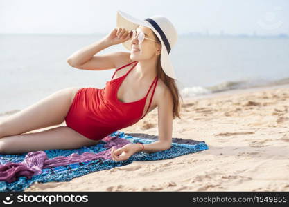 Beautiful woman in red swimsuit is sunbathing on the beach