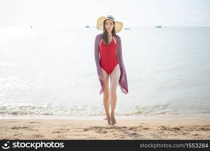 Beautiful woman in red swimsuit is walking from the sea, Summer Concept