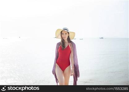 Beautiful woman in red swimsuit is walking from the sea, Summer Concept