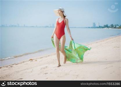 Beautiful woman in red swimsuit is walking on the beach