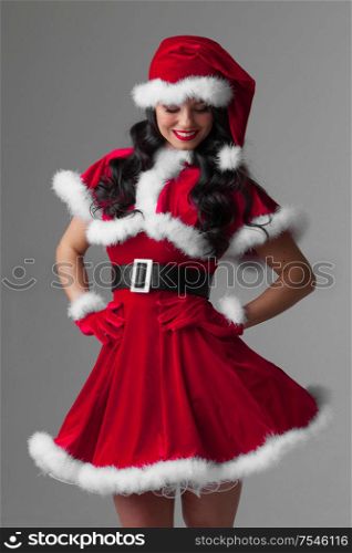 Beautiful woman in Santa Claus clothes on gray background. Woman in Santa Claus clothes