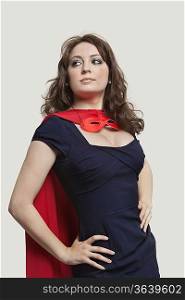 Beautiful woman in superhero costume over gray background