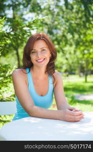 Beautiful woman in the garden sitting near table and waiting for lunch