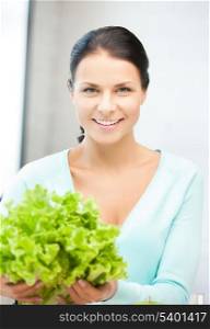 beautiful woman in the kitchen with green salad leaves..