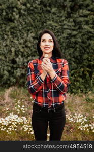 Beautiful woman in the middle of a flowery meadow smelling a daisy