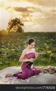 beautiful woman in traditional asian dresses harvesting water lilies in garden. woman harvesting water lilies