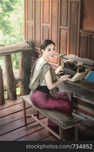 beautiful woman in traditional asian dresses sitting near old typewriter. beautiful woman in traditional asian dresses