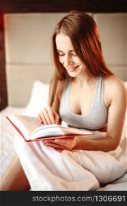 Beautiful woman in underwear reads the book in bed. Girl wake up in the morning in bedroom. Beautiful woman in underwear reads the book in bed