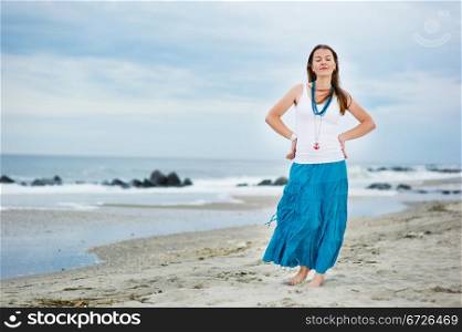 Beautiful woman in white cami and turquoise skirt on the ocean