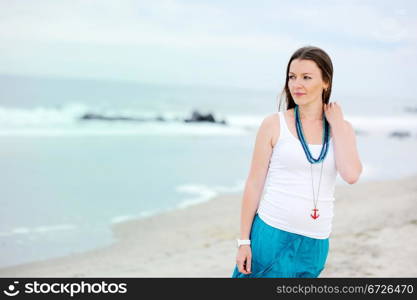 Beautiful woman in white cami and turquoise skirt on the ocean