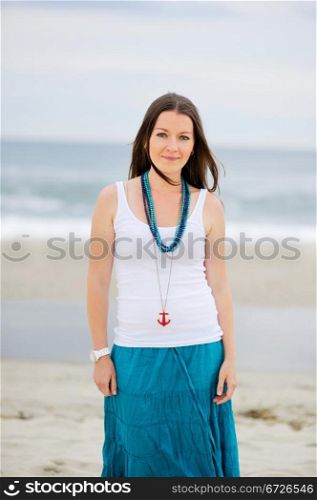 Beautiful woman in white cami and turquoise skirt on the ocean