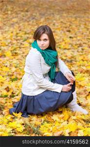 Beautiful woman in white coat and scarf in autumn background with yellow leaf