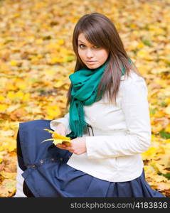 Beautiful woman in white coat and scarf in autumn background with yellow leaf