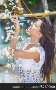 Beautiful woman in white dress. Beautiful woman in white dress on vacation touching a garland of shells and corals