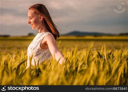 Beautiful woman in white dress on golden yellow wheat field. Beautiful woman in white dress on golden yellow wheat field in warm sunshine under dramatic sky, fresh vibrant colors, at Rhine Valley (Rhine Gorge) in Germany