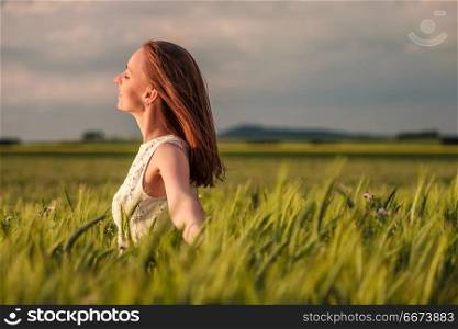 Beautiful woman in white dress on green wheat field. Beautiful woman in white dress on green wheat field in warm sunshine under dramatic sky, fresh vibrant colors, at Rhine Valley (Rhine Gorge) in Germany