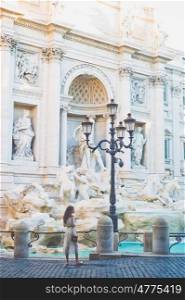 Beautiful woman in white dress take a photo of Trevi Fountain, Rome, Italy. Happy woman enjoy italian vacation. Holiday in Europe. Woman in white dress in front of Trevi Fountain in Rome