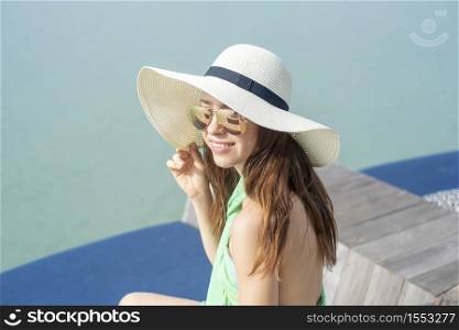 Beautiful woman in white hat is sitting on the hotel with the beach