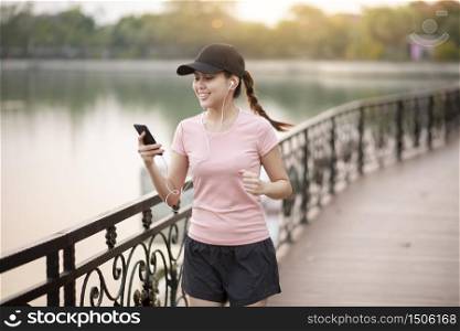 Beautiful woman is listening music and jogging in the park