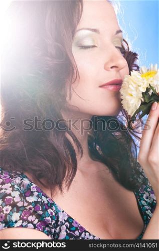 beautiful woman is pleasured with flower on blue background