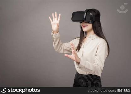 beautiful woman is using virtual reality on gray background