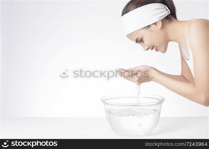 Beautiful woman is washing her face on white background