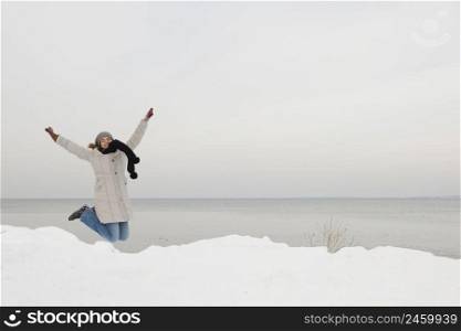 Beautiful woman jumping and enjoying a winter day full of snow