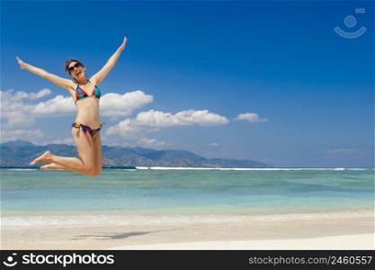 Beautiful woman jumping on a beautiful tropical beach