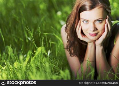 Beautiful woman laying in a green field enjoying the summer sunlight