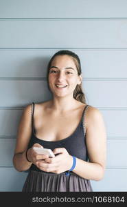 Beautiful woman leaning on a wood wall while using a smartphone