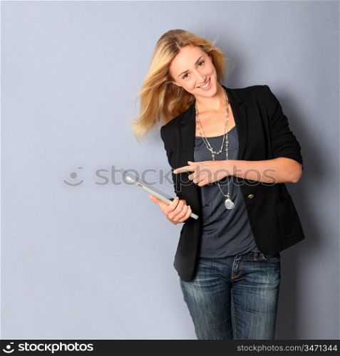 Beautiful woman leaning on wall with touchpad