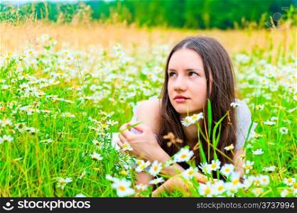 beautiful woman lies in a green field with flowers