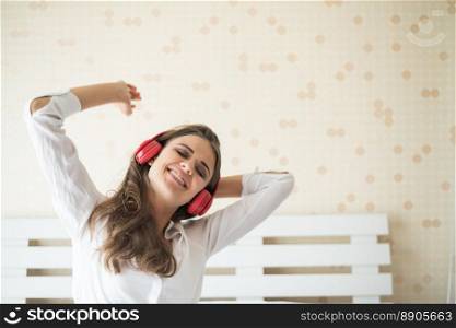 Beautiful woman listening music in morning sitting on bed at home