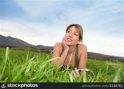 Beautiful woman listening to music in natural field
