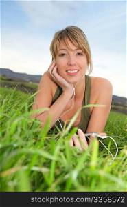 Beautiful woman listening to music in natural field