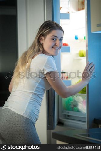 Beautiful woman looking inside the refrigerator on kitchen at night