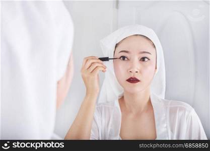 Beautiful woman looking mirror and make-up with black eyeliner