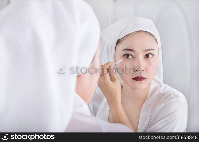 Beautiful woman looking mirror and remove makeup beside eye with a cotton swab