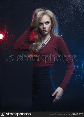 Beautiful woman looking through the window with rain drops