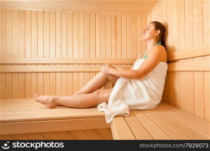 Beautiful woman lying on bench at scandinavian sauna