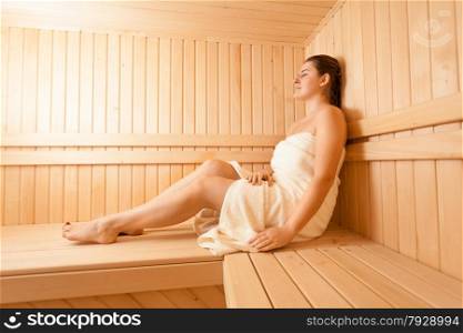 Beautiful woman lying on bench at traditional sauna