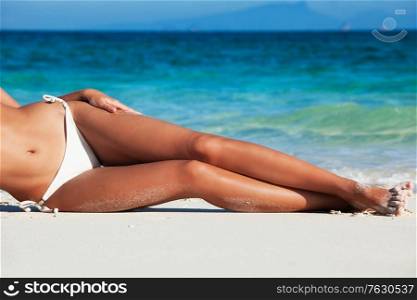Beautiful woman lying on sea shore in white bikini. Woman lying on sea shore in bikini