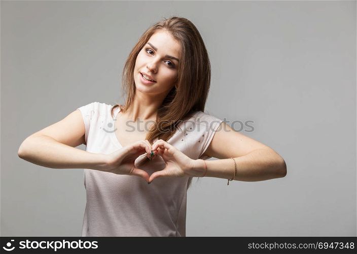 Beautiful woman making a heart symbol with her hands. Beautiful woman making a heart symbol with her hands, studio portrait