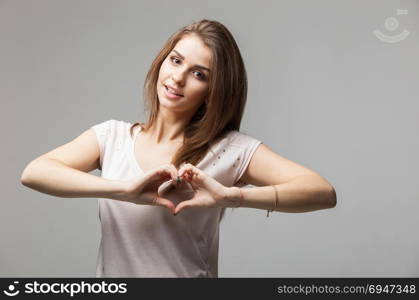 Beautiful woman making a heart symbol with her hands. Beautiful woman making a heart symbol with her hands, studio portrait