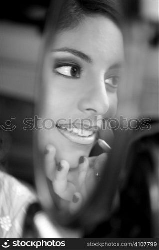 beautiful woman making up and looking into a round mirror