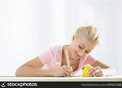 Beautiful woman marking table with measure tape