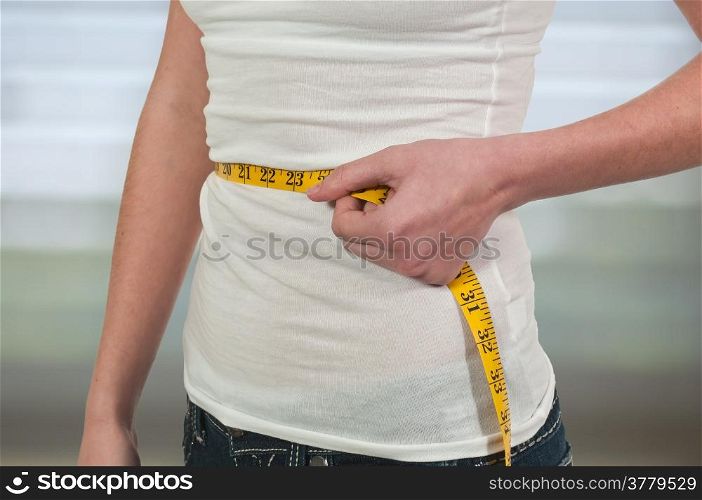 Beautiful woman measuring her waist with a tailors tape