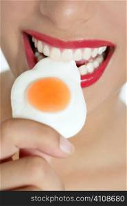 Beautiful woman mouth with red lips eating a jelly egg